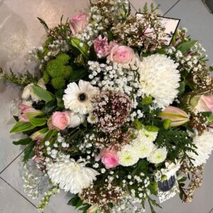Coussin de fleurs fraîches piquées dans la mousse réalisé en camaïeu de rose et blanc